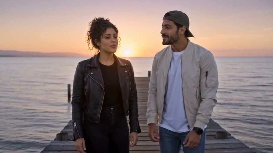 A woman and a man on a seaside pier at sunset